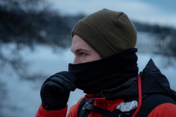 Excursionista en la montaña nevada con una braga de cuello de forro polar subida hasta la nariz