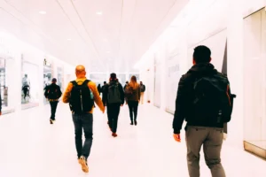 Viajeros caminando por una terminal de aeropuerto luminosa con mochilas como equipaje de mano
