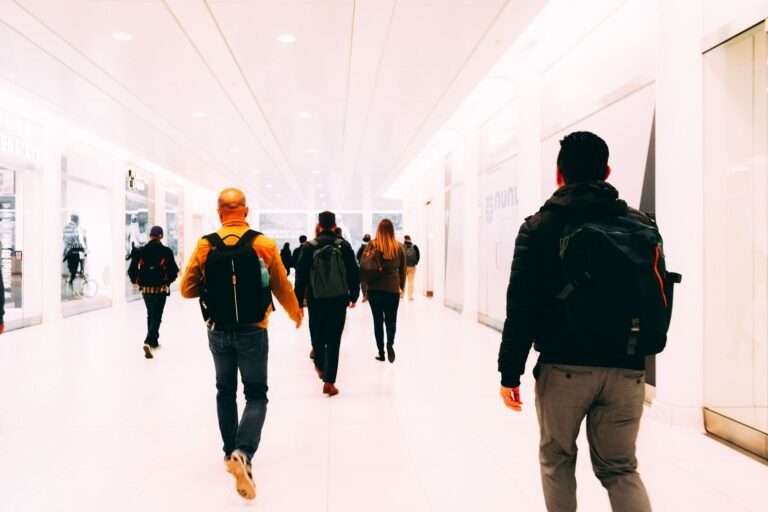 Viajeros caminando por una terminal de aeropuerto luminosa con mochilas como equipaje de mano
