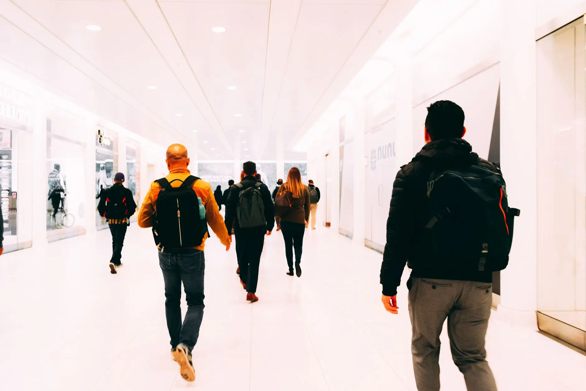 Viajeros caminando por una terminal de aeropuerto luminosa con mochilas como equipaje de mano