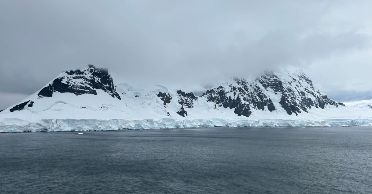 Montañas nevadas e icebergs en la Antártida bajo un cielo nublado