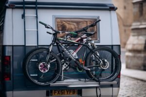 Dos bicicletas de montaña sujetas en un portabicicletas trasero sobre una camper aparcada en la montaña