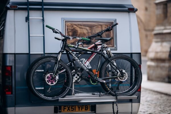 Dos bicicletas de montaña sujetas en un portabicicletas trasero sobre una camper aparcada en la montaña