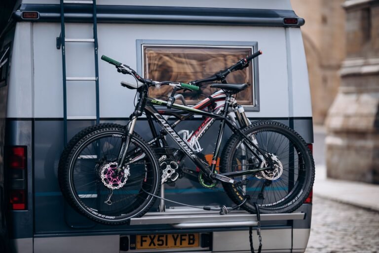 Dos bicicletas de montaña sujetas en un portabicicletas trasero sobre una camper aparcada en la montaña