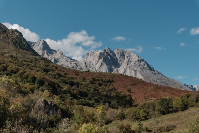 Paisaje de montaña verde en Asturias con cumbres al fondo