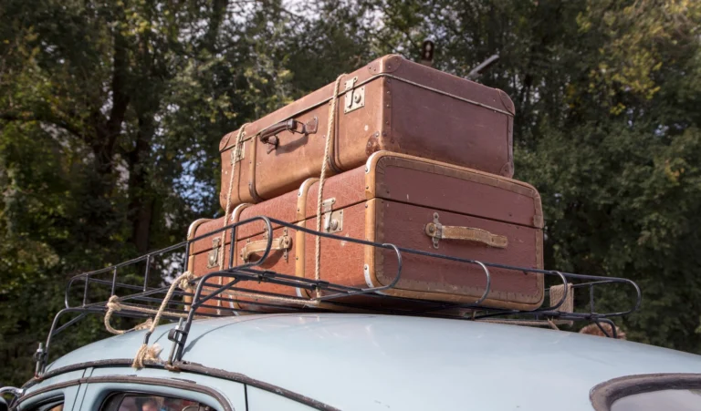 Maletas sujetas en la baca del techo de un coche antiguo preparado para un viaje por carretera