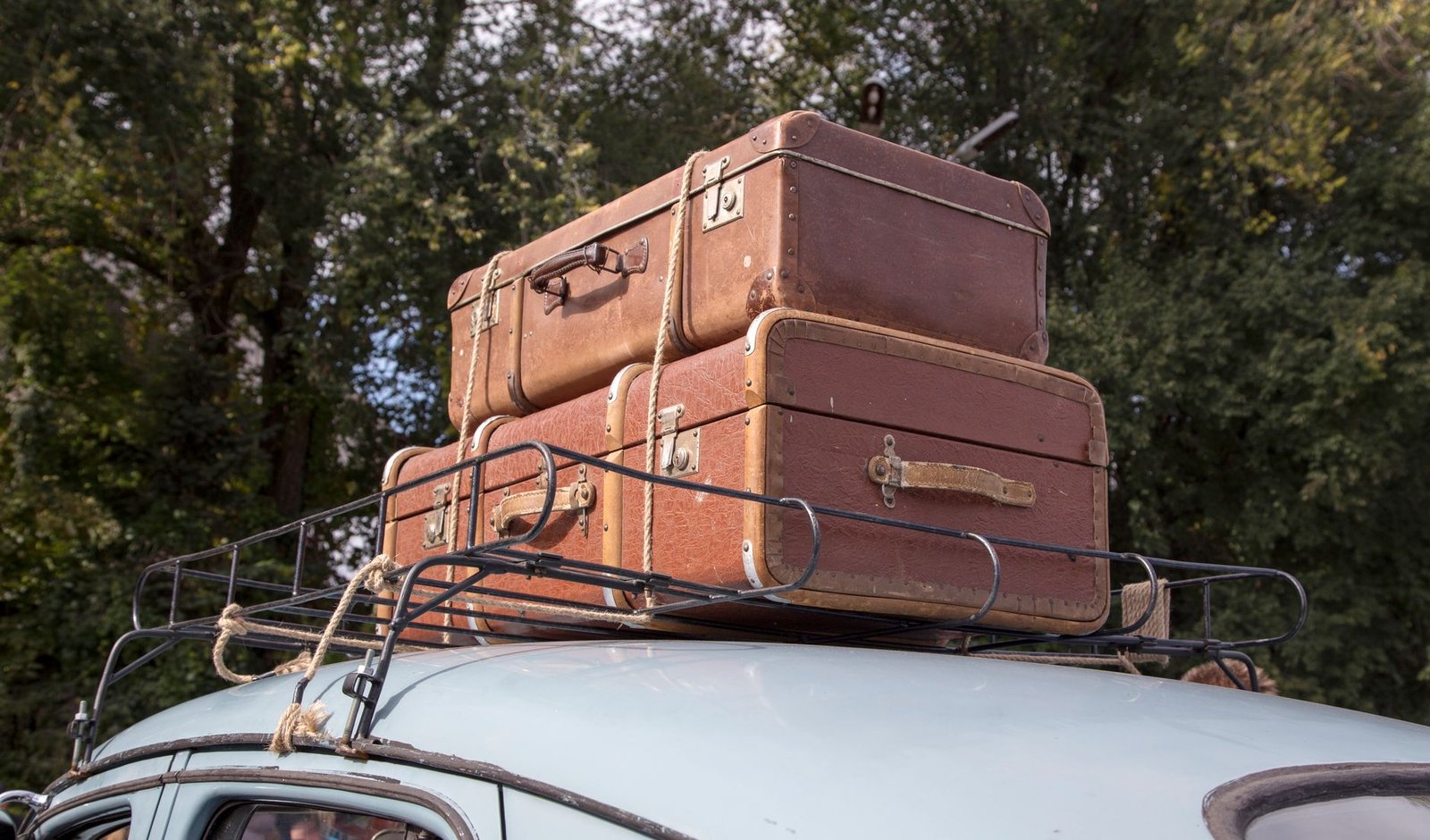 Maletas sujetas en la baca del techo de un coche antiguo preparado para un viaje por carretera