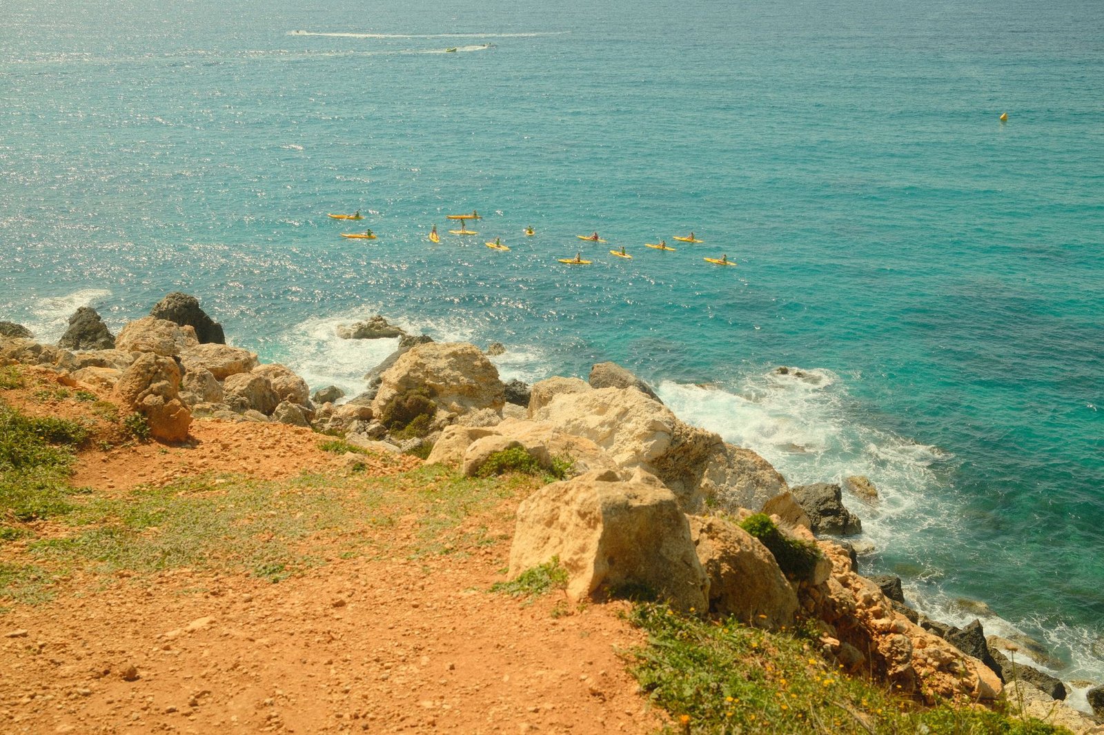 Kayaks navegando junto a una costa rocosa de aguas cristalinas