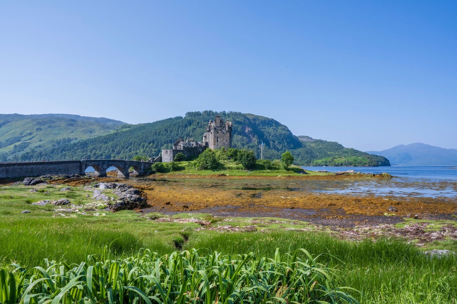 Castillo escocés rodeado de un paisaje verde junto a un lago
