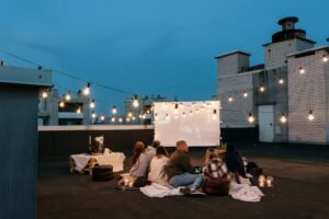 Grupo de amigos viendo una película al aire libre en una azotea con un proyector portátil