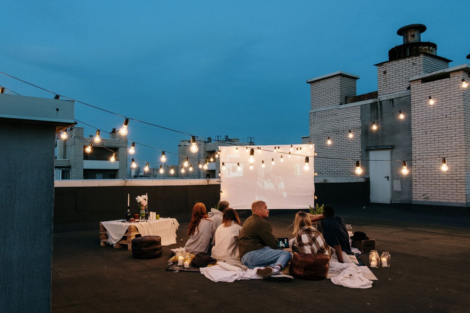 Grupo de amigos viendo una película al aire libre en una azotea con un proyector portátil