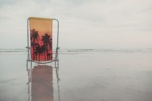 Silla de playa plegable con diseño de palmera en la arena junto al mar