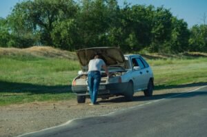 Conductor junto a su coche averiado en el arcén de la carretera