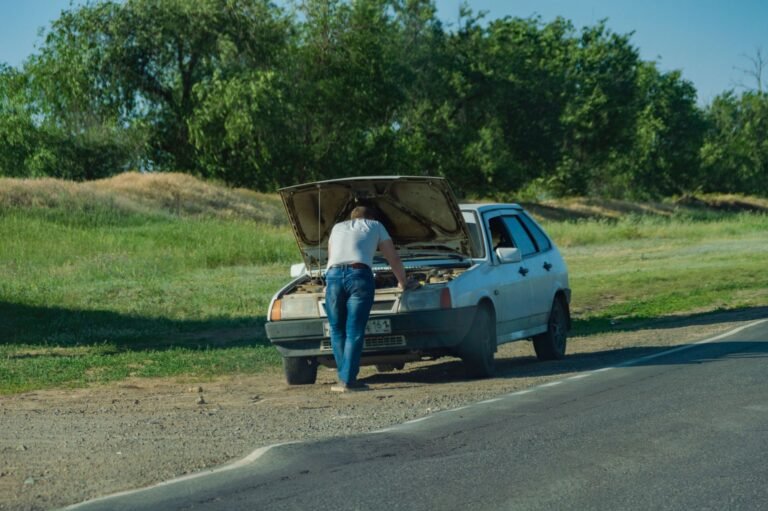 Conductor junto a su coche averiado en el arcén de la carretera