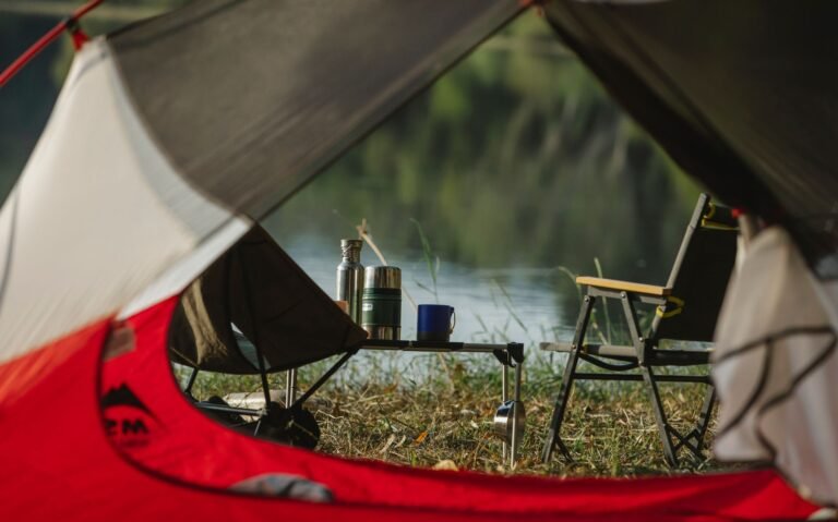 Mesa y sillas plegables de camping montadas junto a un lago
