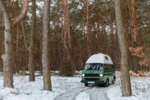 Furgoneta camper aparcada en un bosque nevado en invierno