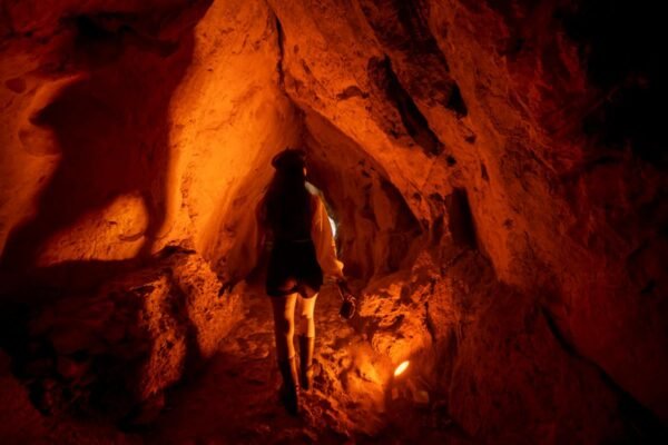 Exploradora con frontal recorriendo una cueva en España