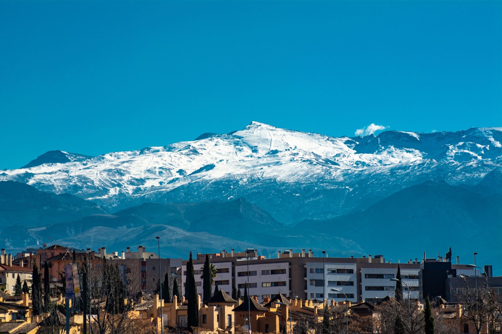 Sierra Nevada imponente sobre la ciudad de Granada en un día despejado de verano