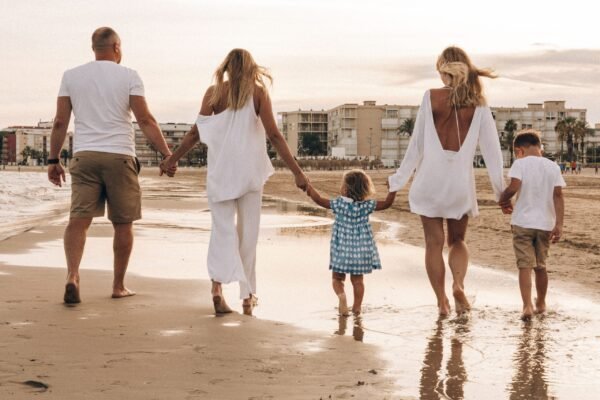 Familia caminando por la playa al atardecer disfrutando de las vacaciones de verano