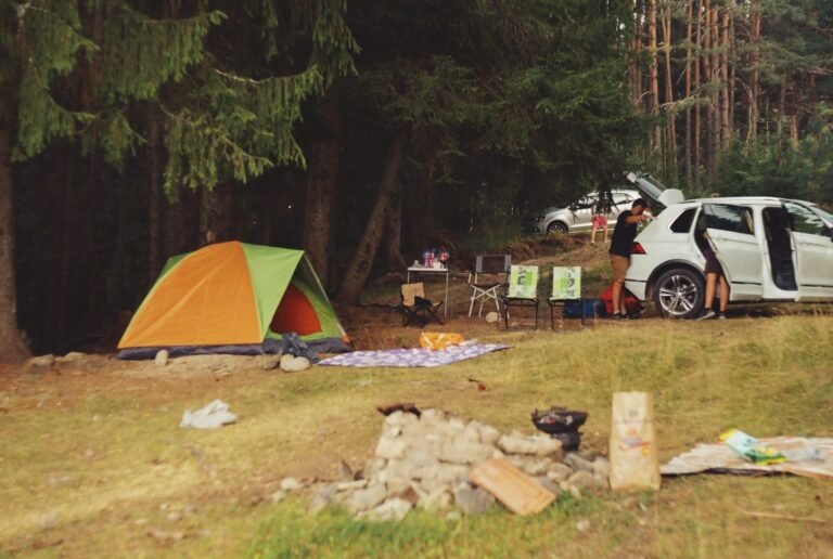 Tienda de campaña familiar montada junto al coche en un camping forestal