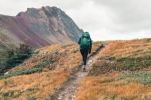 Senderista con mochila grande de trekking recorriendo un sendero de montaña en otoño