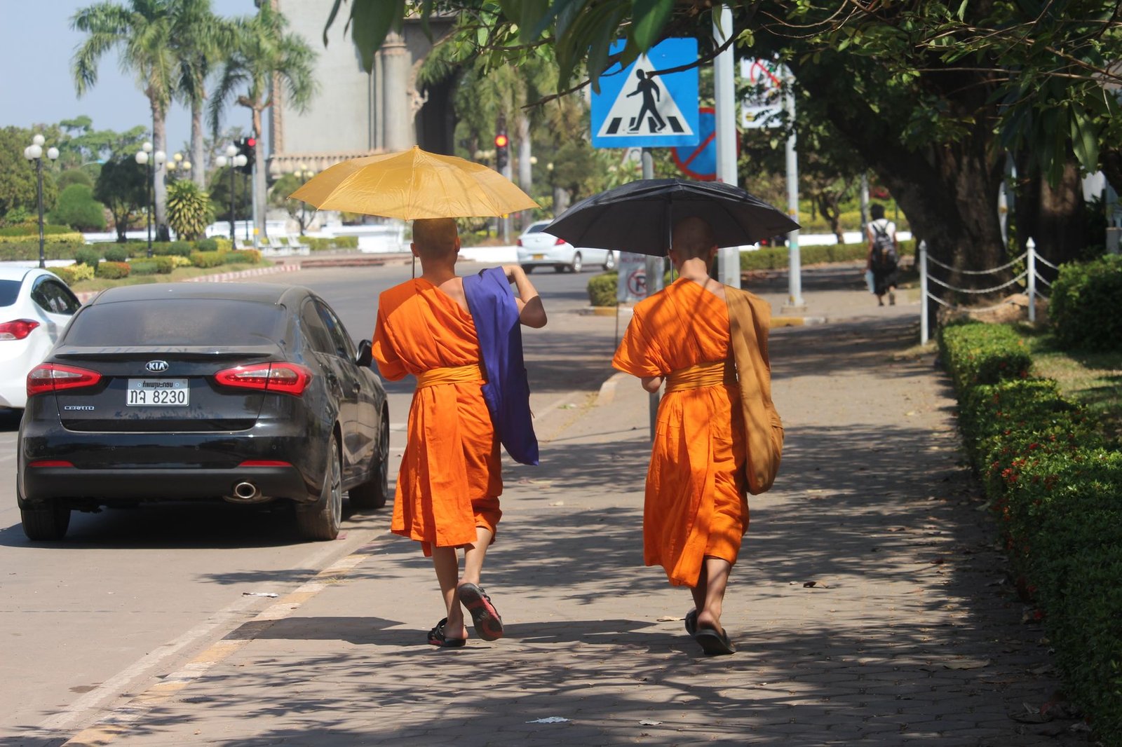 Dos monjes budistas caminan bajo paraguas por una calle de Vientián