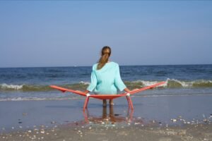 Mujer descansando en una tumbona plegable frente al mar en un día soleado