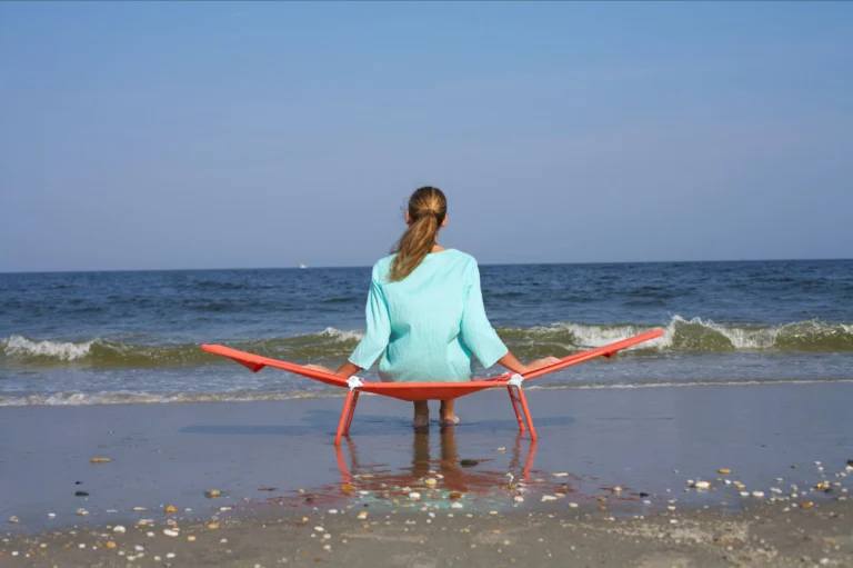 Mujer descansando en una tumbona plegable frente al mar en un día soleado