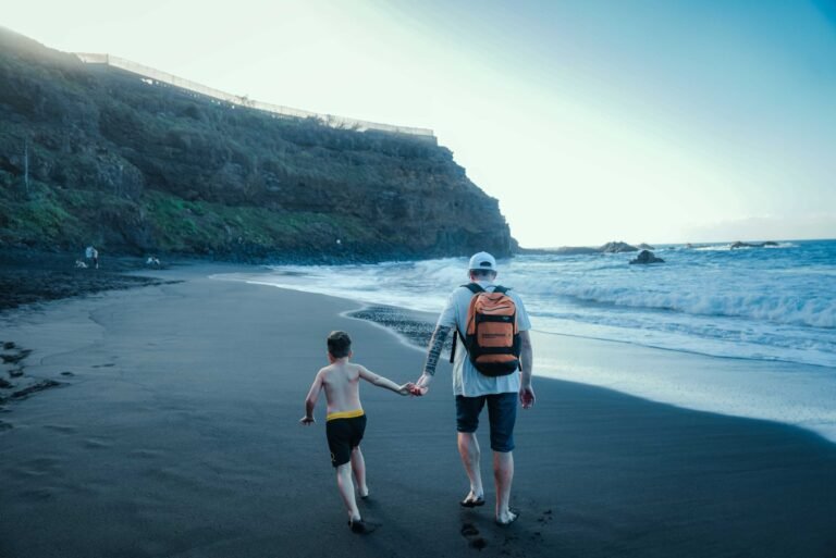 Padre e hijo caminan de la mano por una playa de arena en Tenerife