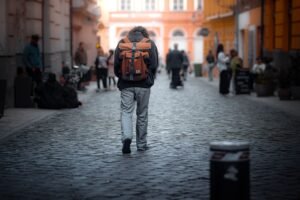 Viajero con mochila caminando solo por una calle adoquinada entre gente en la ciudad