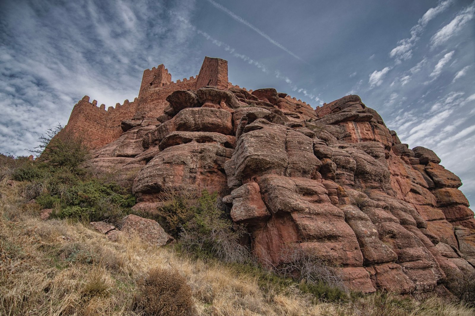 Fortaleza medieval de piedra en lo alto de un cerro, similar al castillo de Calatrava la Nueva en Aldea del Rey