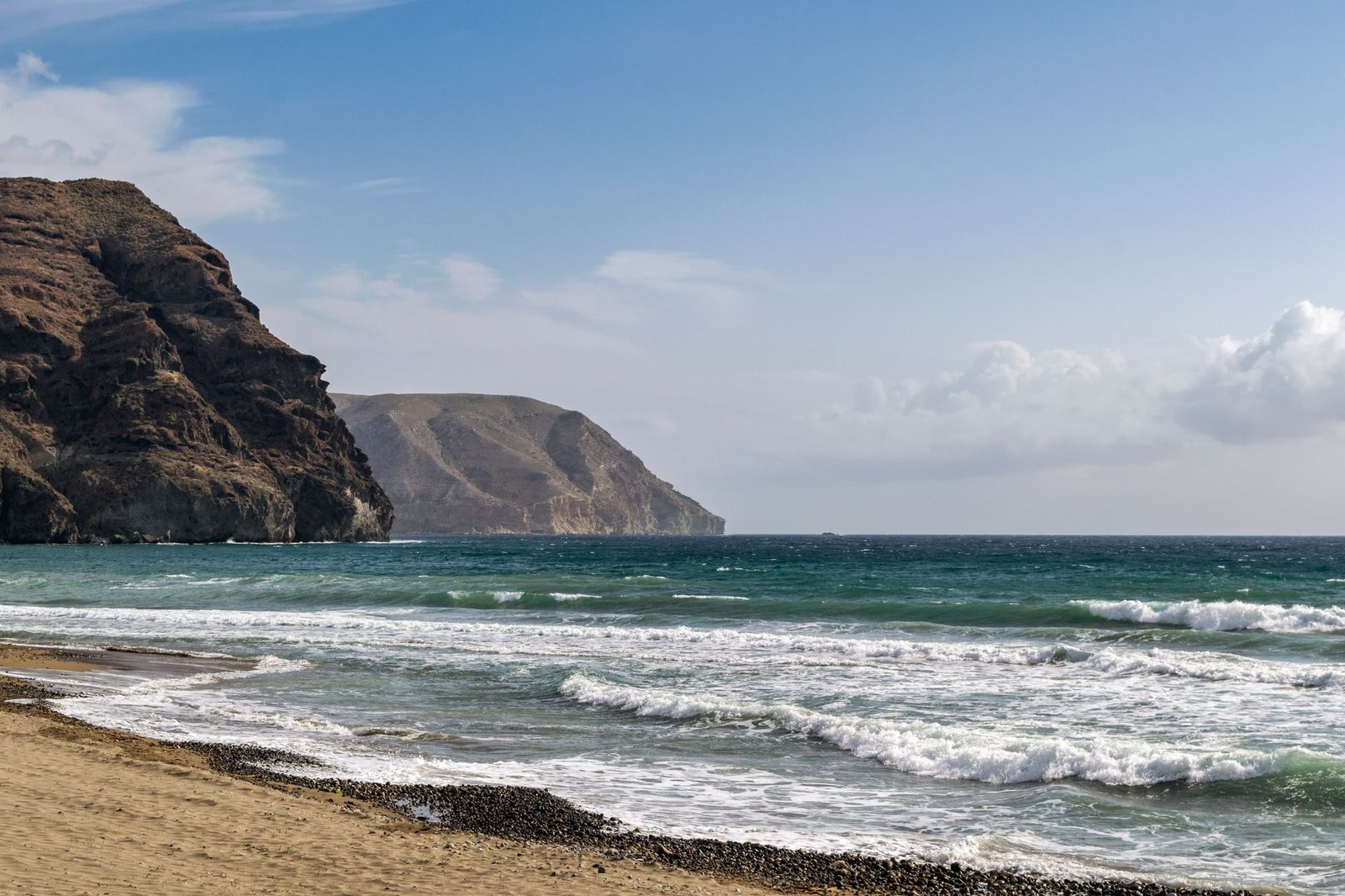 Cala de Las Negras con oleaje y cerros rocosos en la costa de Cabo de Gata