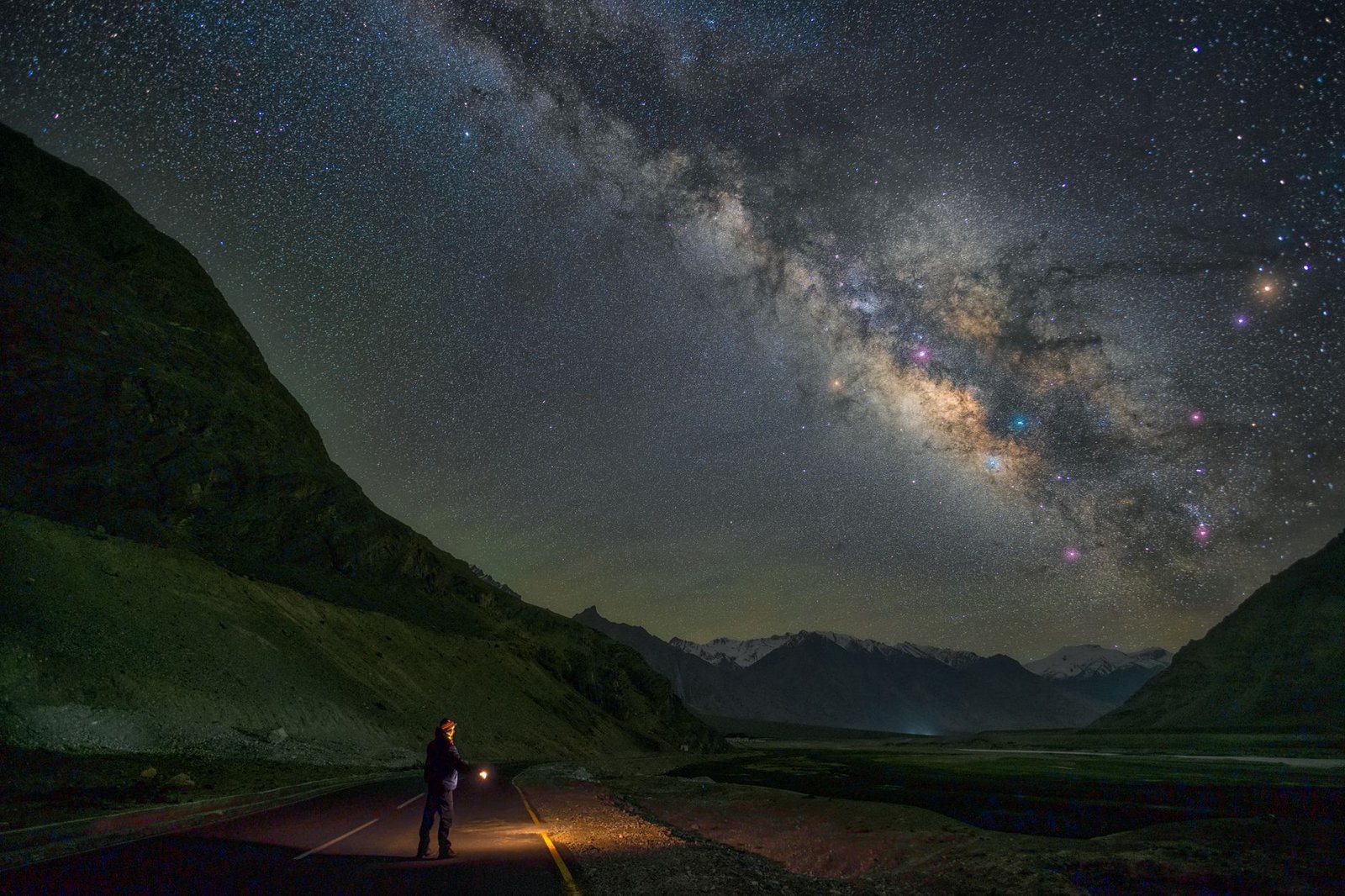 Persona observando la Vía Láctea desde una zona de montaña con cielo oscuro