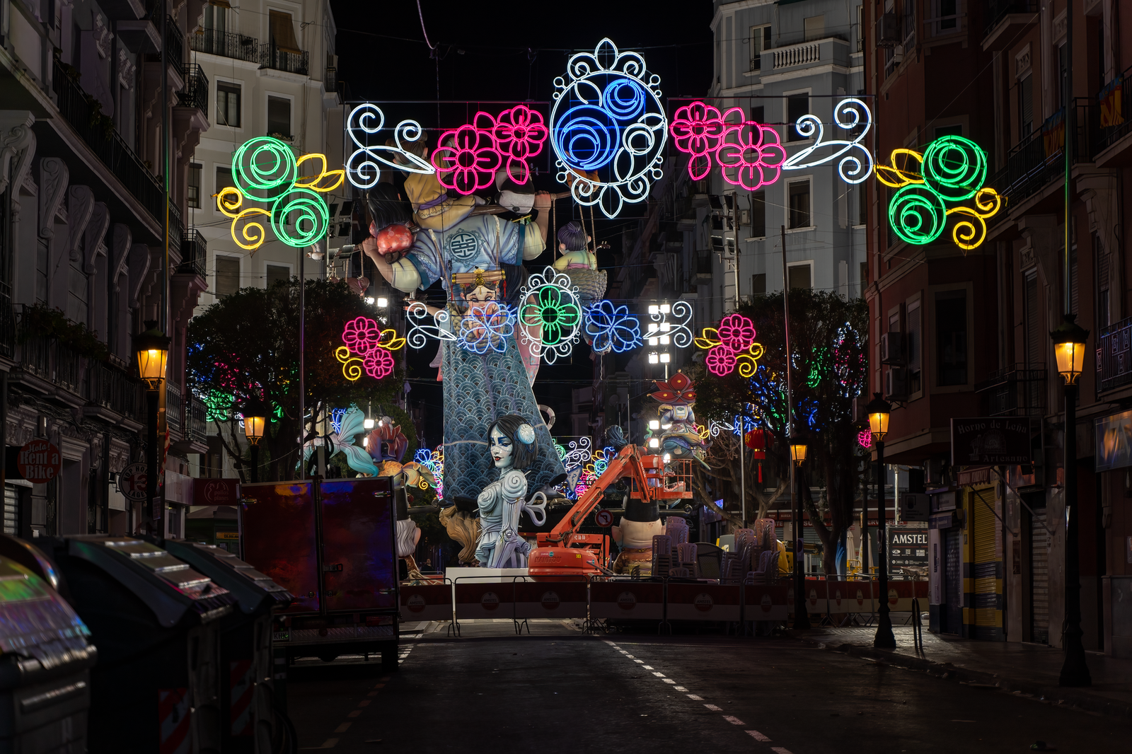 Ninots iluminados de una falla en una calle de Valencia por la noche