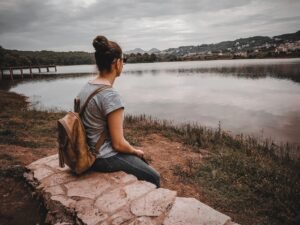 Mujer sentada en un muro de piedra junto a un lago en Albania