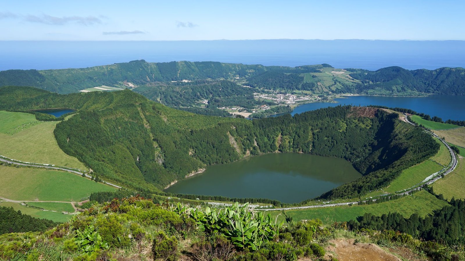 Laguna de origen volcánico rodeada de vegetación mediterránea, similar a los maares del Geoparque Volcanes de Calatrava