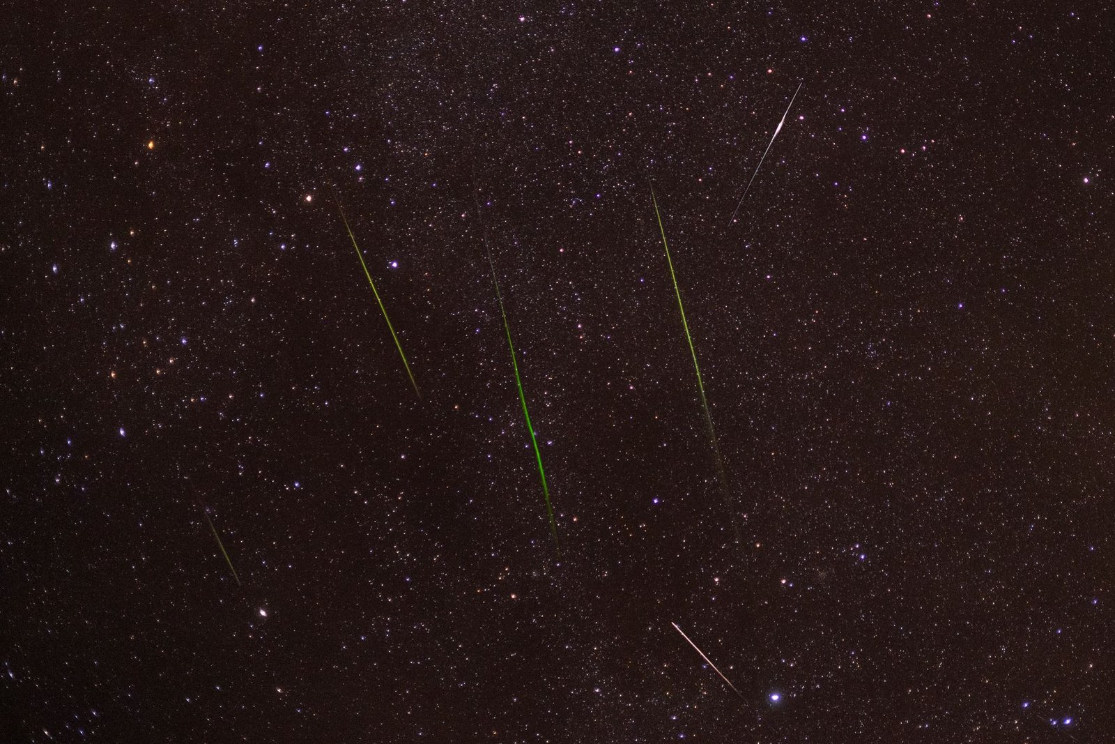 Varios meteoros brillantes cruzando un cielo estrellado durante una lluvia de estrellas