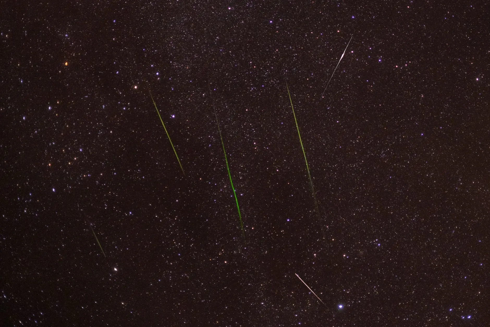 Varios meteoros brillantes cruzando un cielo estrellado durante una lluvia de estrellas