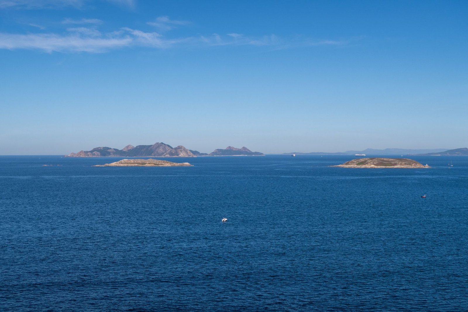 Siluetas de las islas Cíes sobre el mar bajo un cielo despejado vistas desde la ría de Vigo