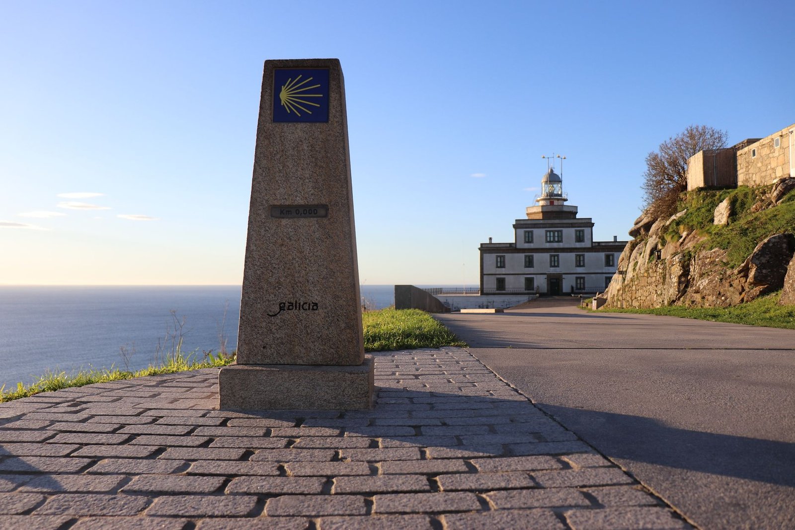Faro de Cabo Fisterra en Galicia, con el hito del kilómetro cero, bajo un cielo despejado