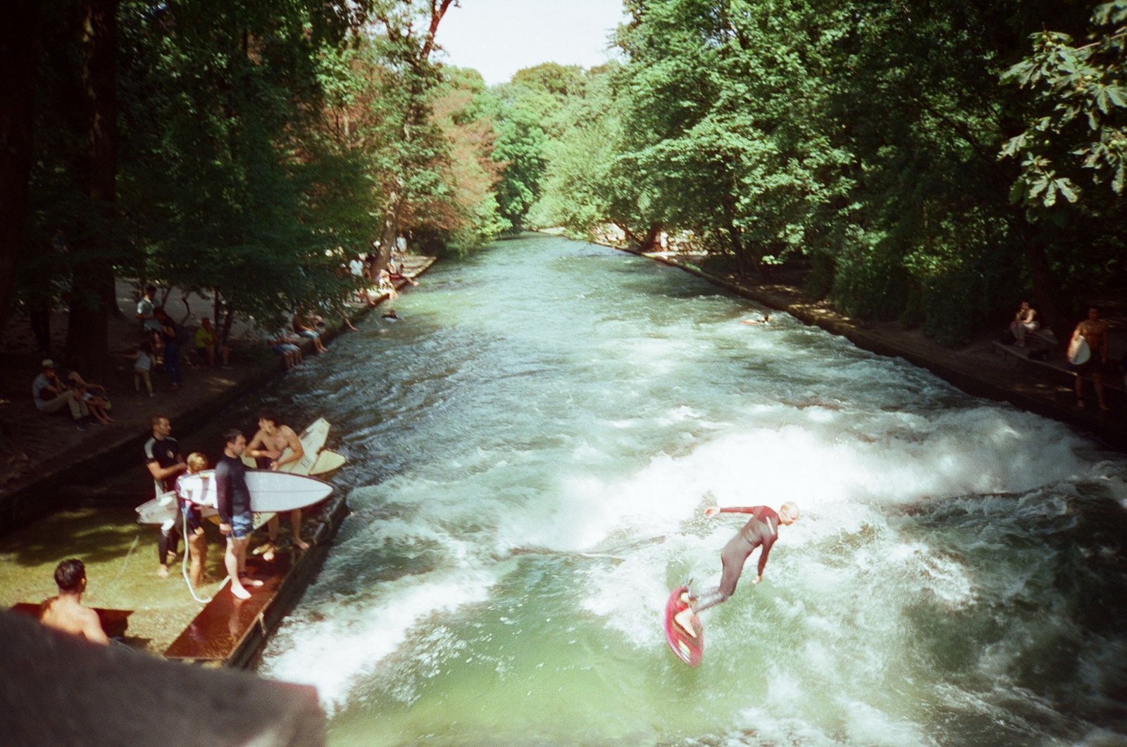 Surfistas en la ola del Eisbach a la entrada del Jardín Inglés de Múnich