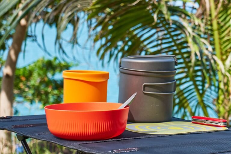 Menaje de camping plegable: vajilla, ollas y cubiertos sobre una mesa plegable al aire libre