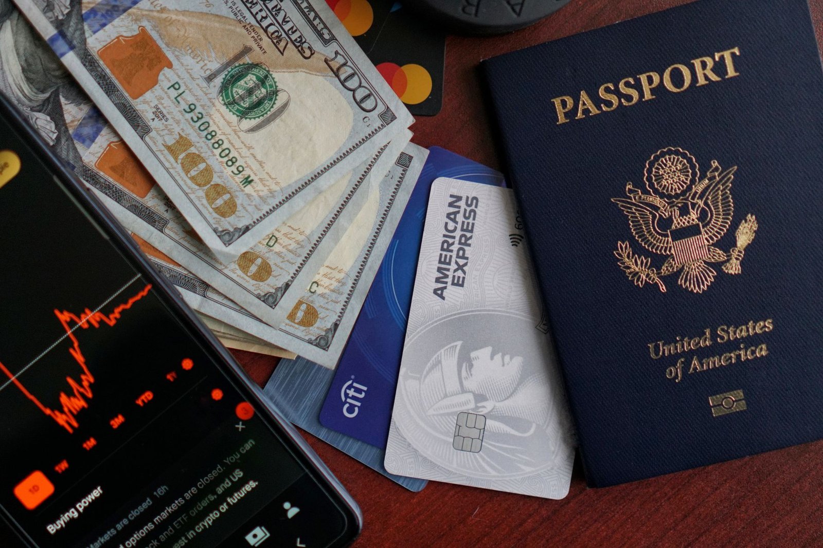 Pasaporte, tarjetas de crédito, billetes y móvil sobre una mesa, preparados para un viaje al extranjero
