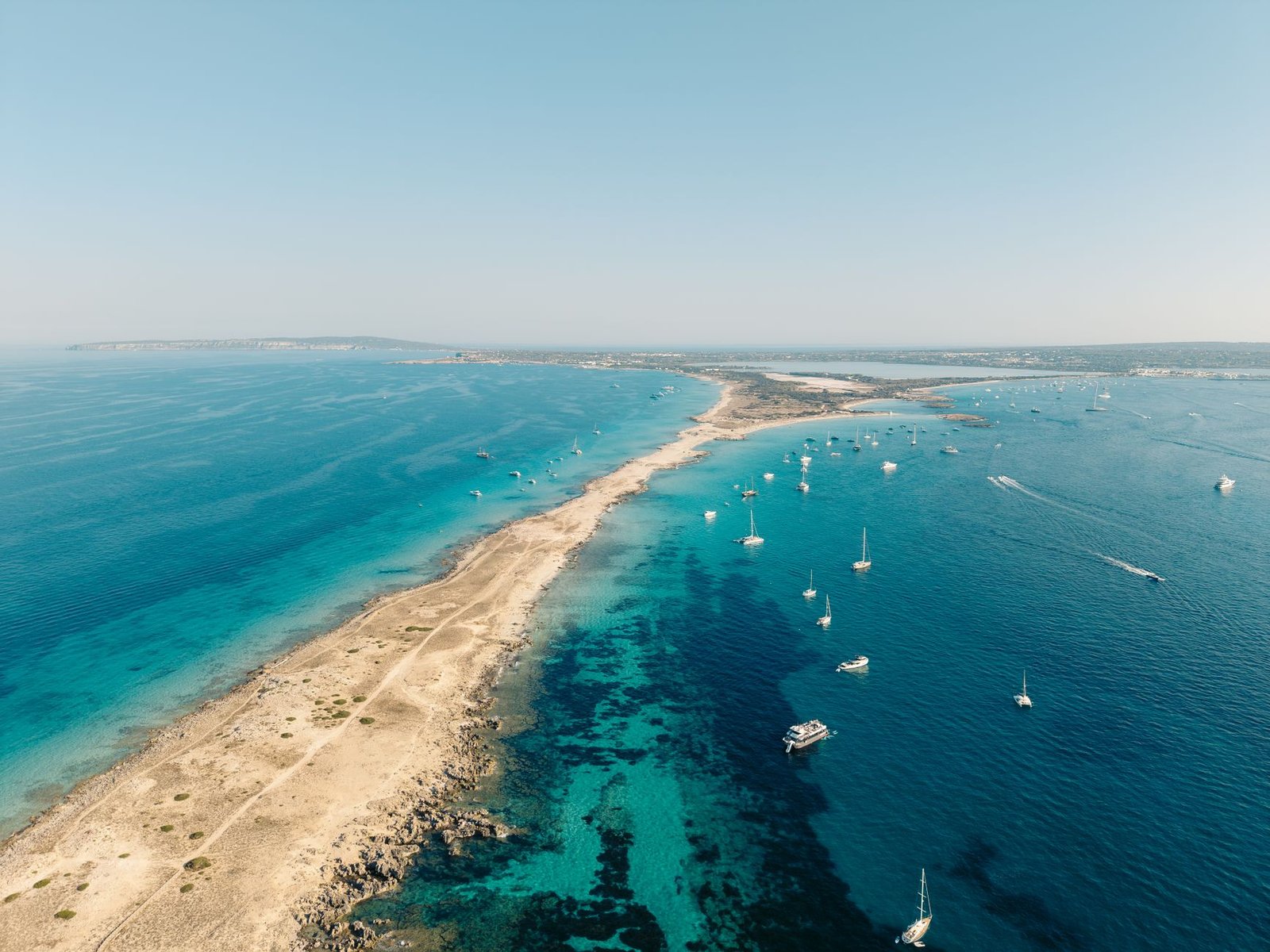 Vista aérea del litoral de Formentera con veleros fondeados sobre agua turquesa