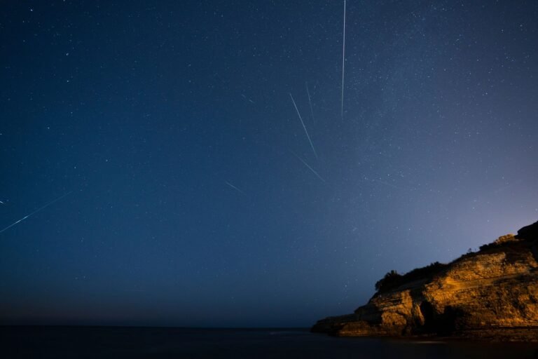 Meteoros de las Perseidas cruzando el cielo nocturno sobre un acantilado