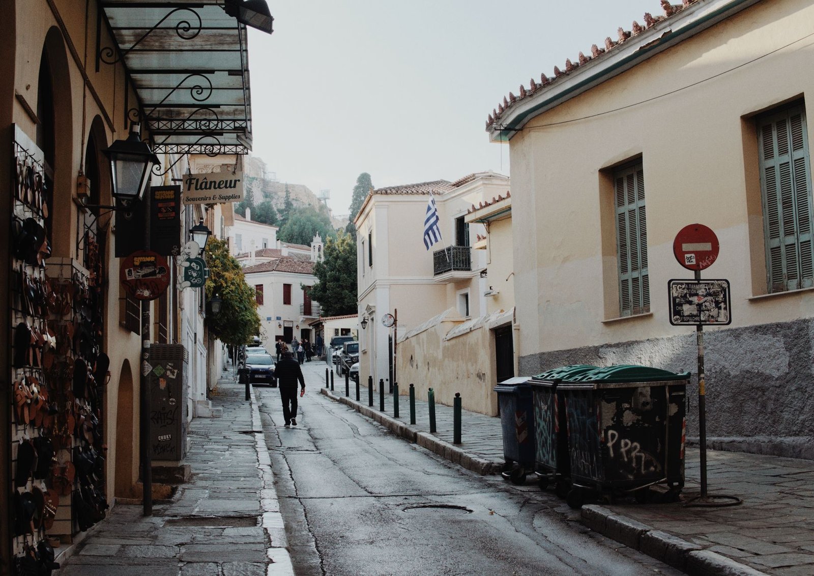 Calle tranquila del barrio de Plaka en Atenas con una bandera griega