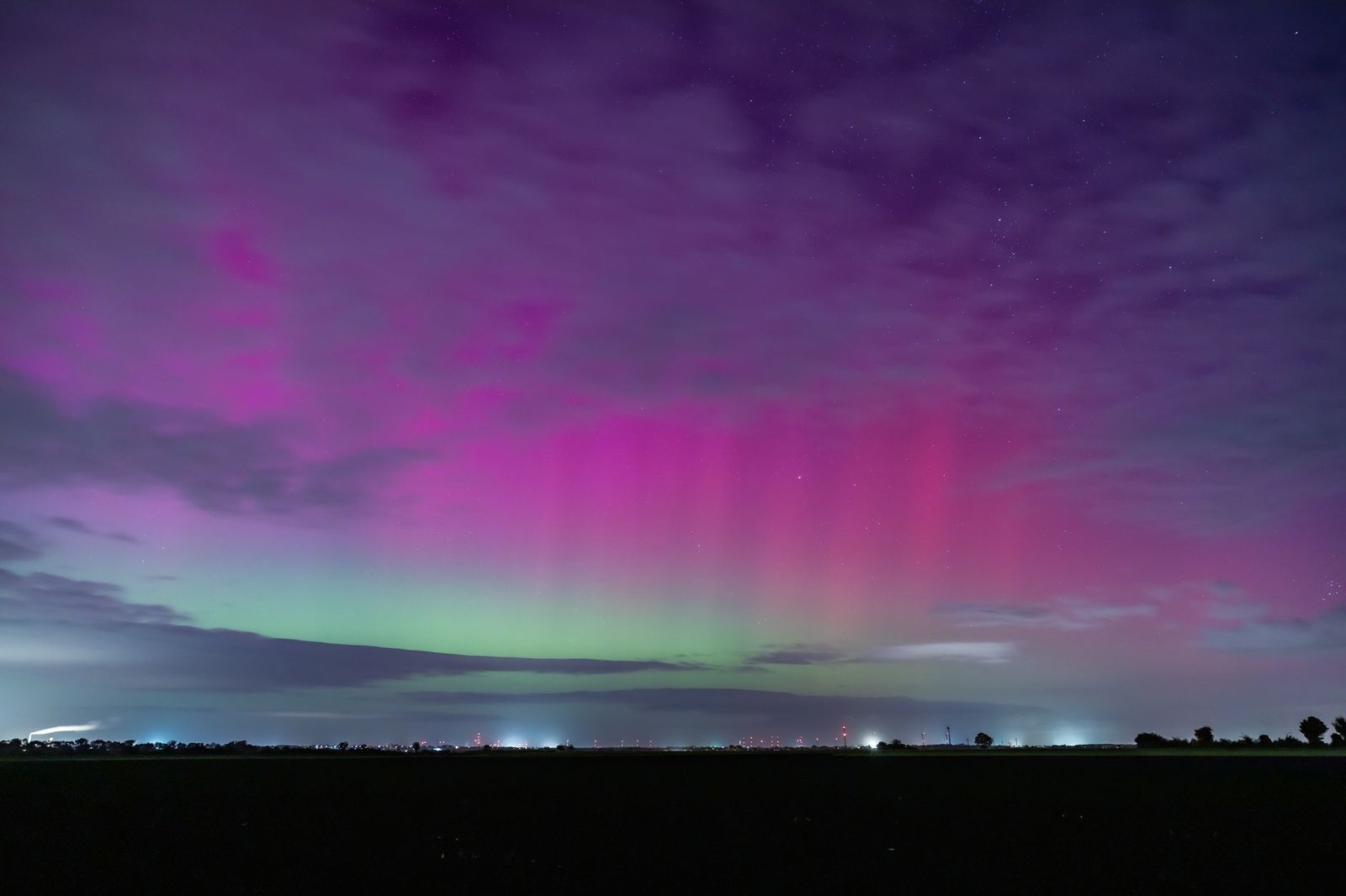 Aurora boreal con tonos morados y verdes en el cielo nocturno