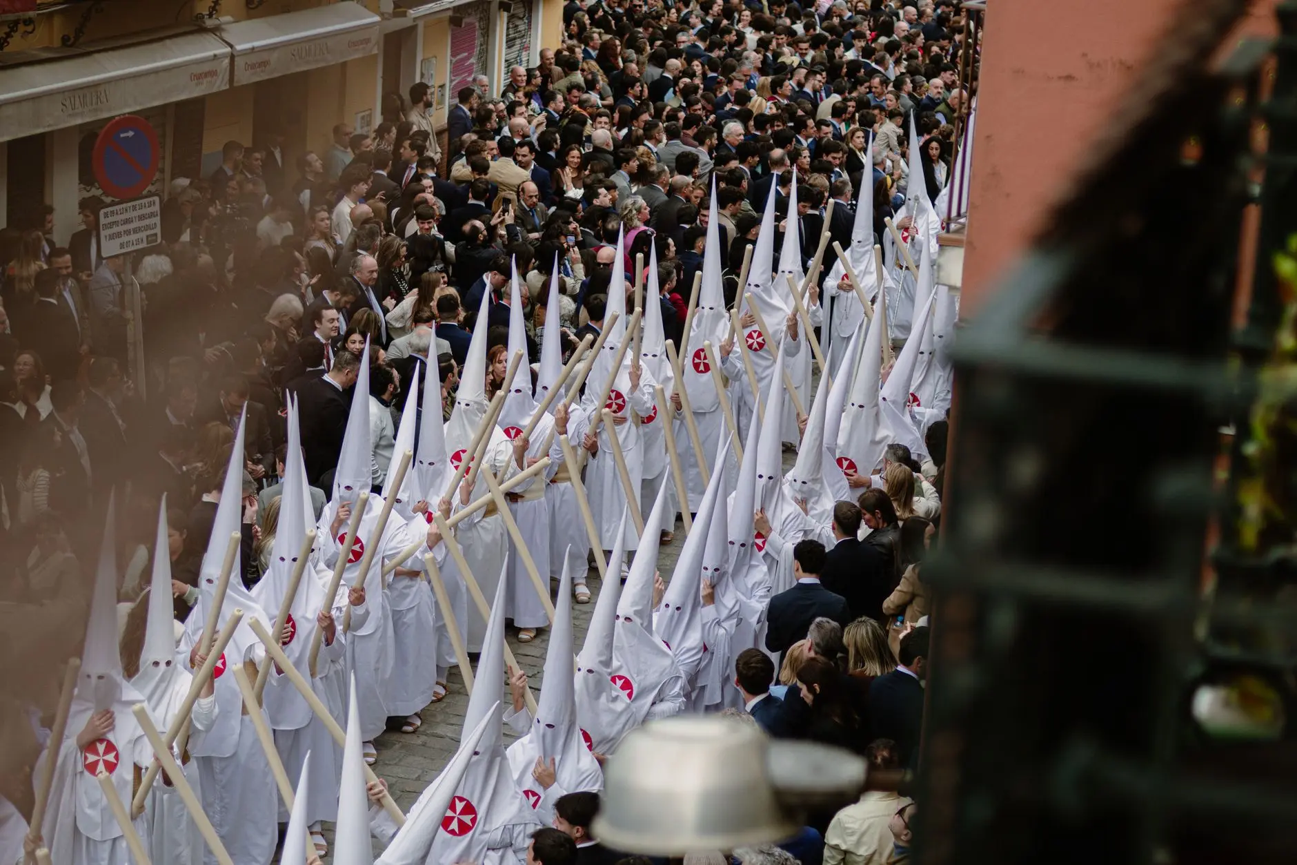 Larga fila de nazarenos con capirote en una procesión de Semana Santa en Sevilla