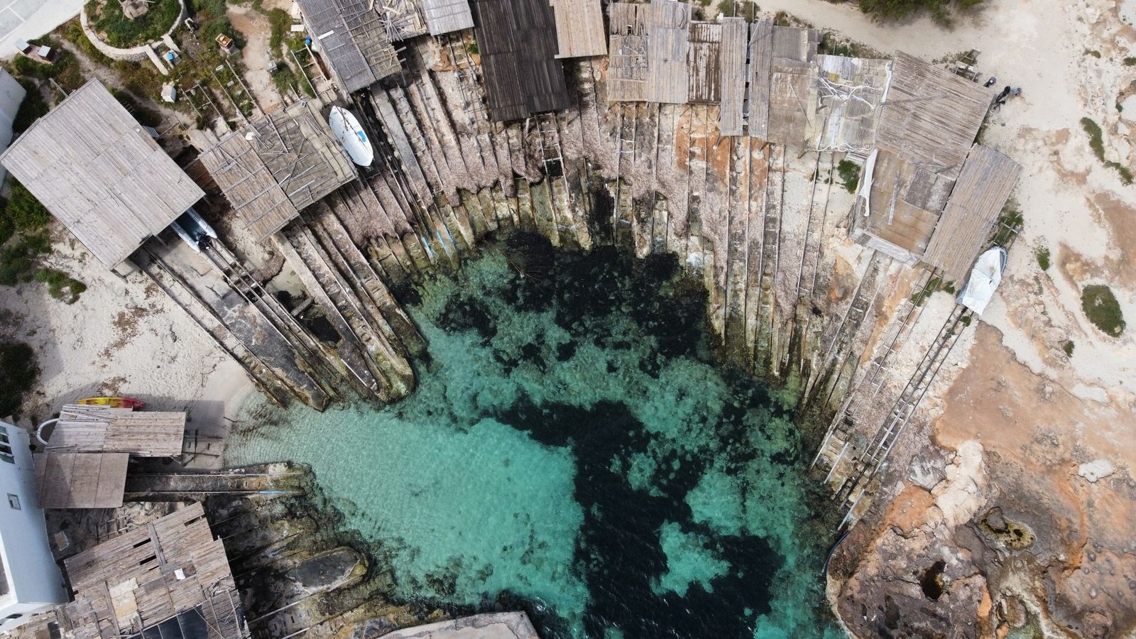 Casetas varadero tradicionales y agua turquesa en Es Caló de Sant Agustí, Formentera