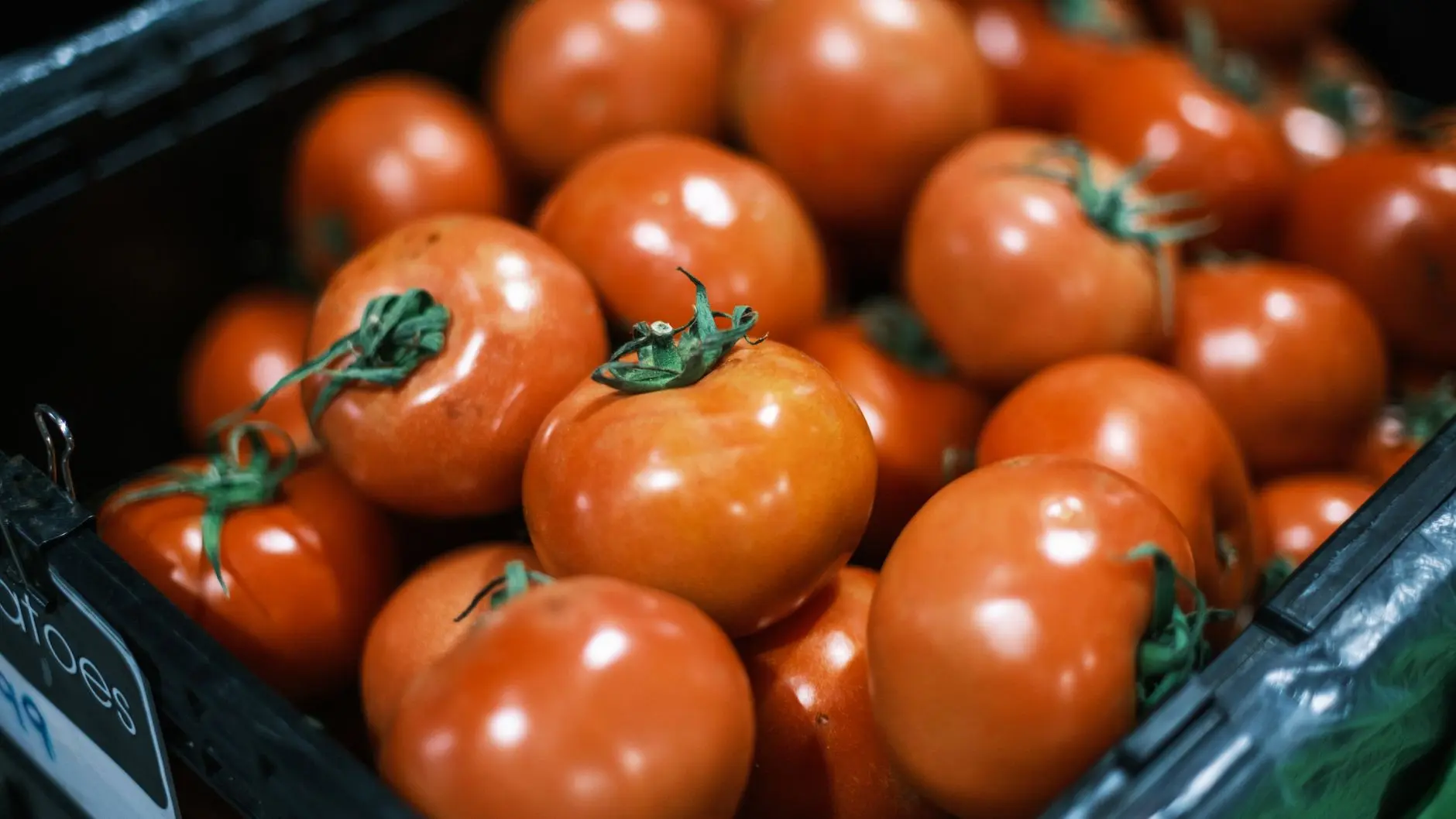 Tomates rojos maduros apilados en una caja de mercado